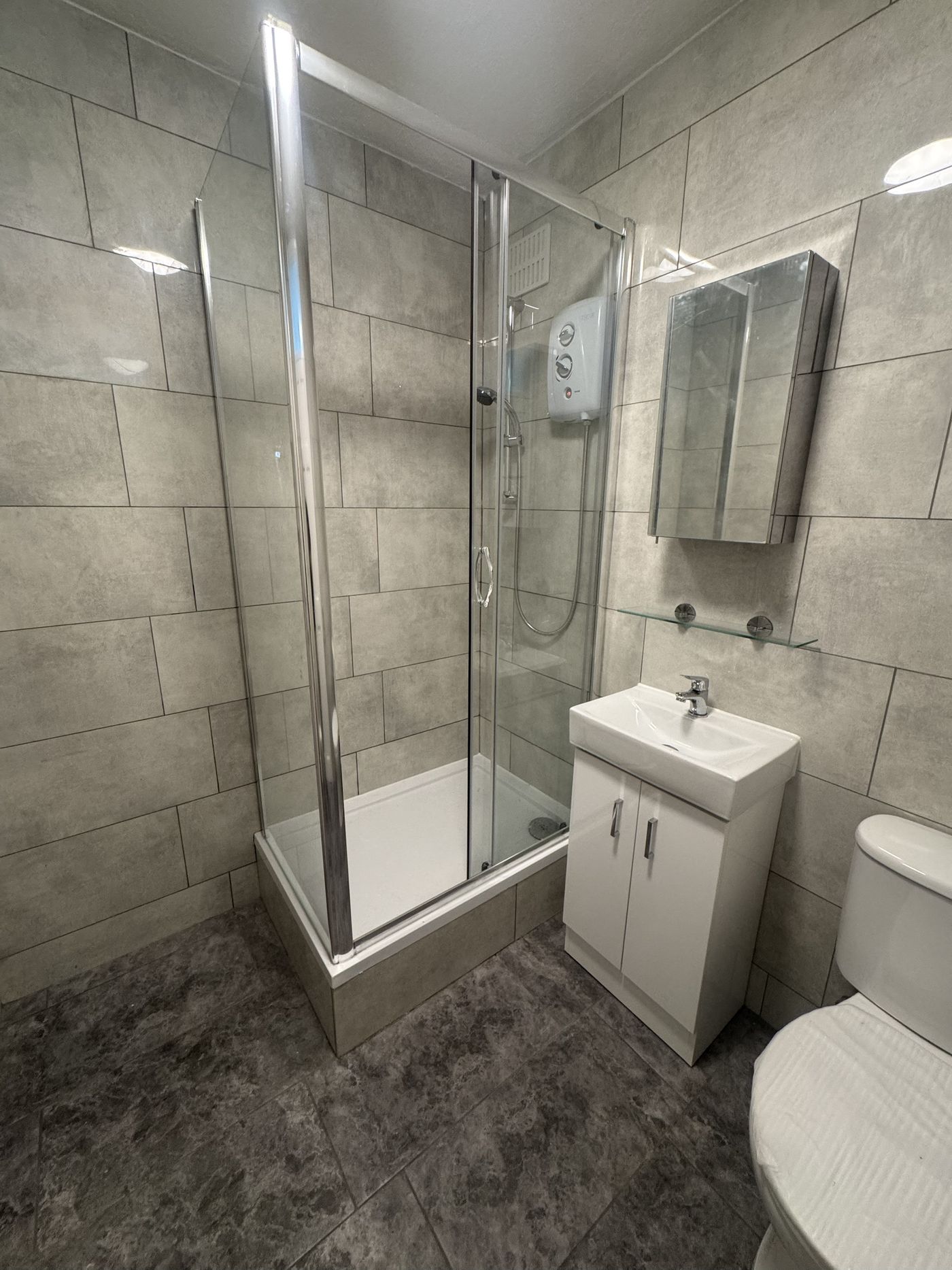 Finished bathroom with a walk-in shower, tiled walls and new vanity unit