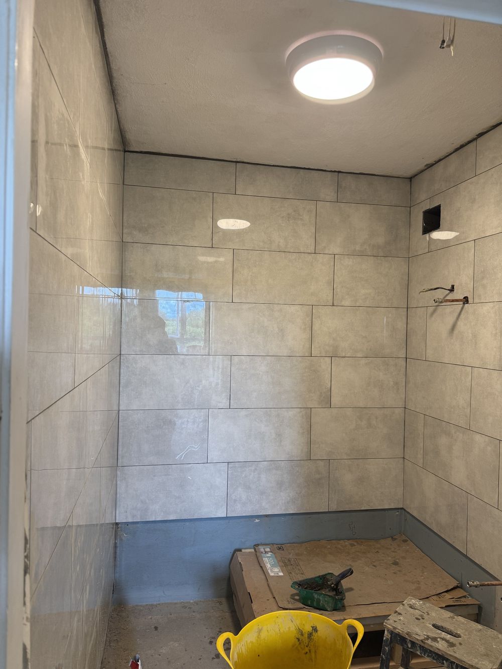 Bathroom mid-renovation with fresh tiling and waterproofing visible at the base